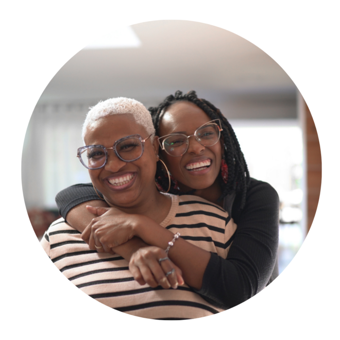 Two women cuddling and smiling in a living room.