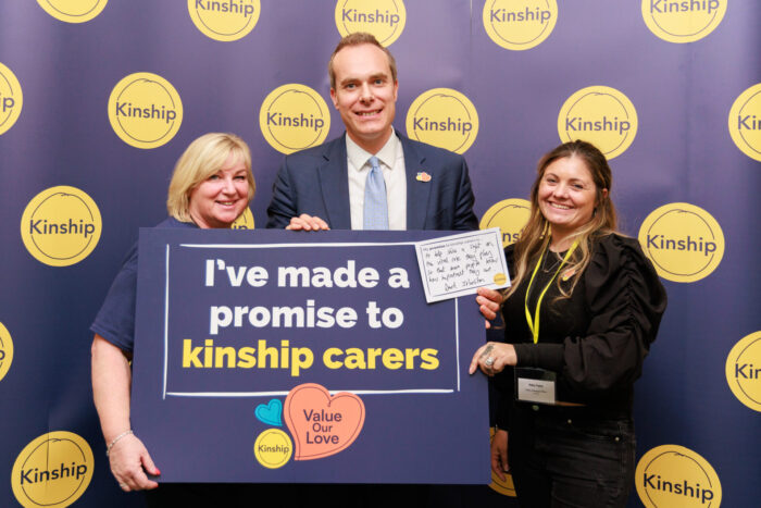 David Johnston MP standing with 2 kinship campaigners holding a placard with the Value Our Love logo and writing that says 