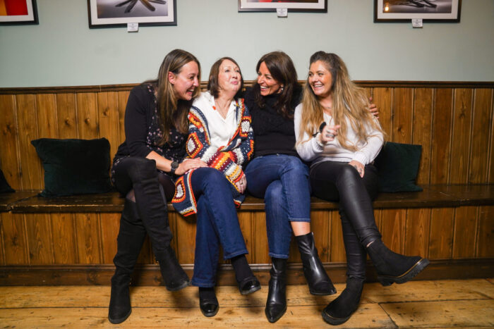 Davina McCall sits with three kinship carers. They are all laughing and smiling.