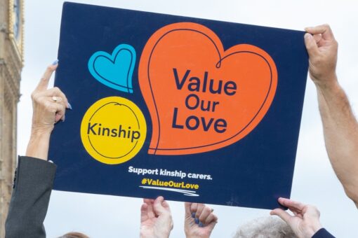 A close-up of a placard with the Value Our Love logo held aloft in the air.