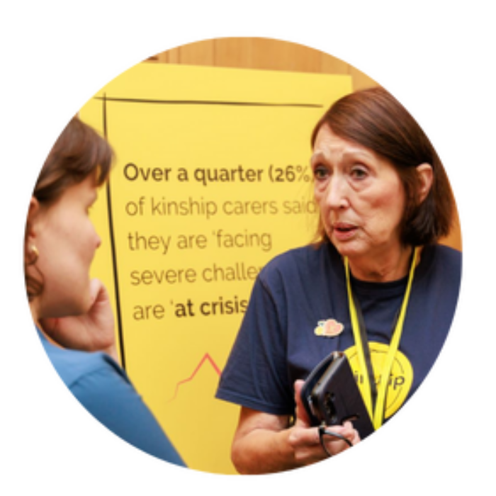 Kinship campaigner Wendy, wearing a navy blue Kinship T-shirt, talking to someone at a campaigning event.