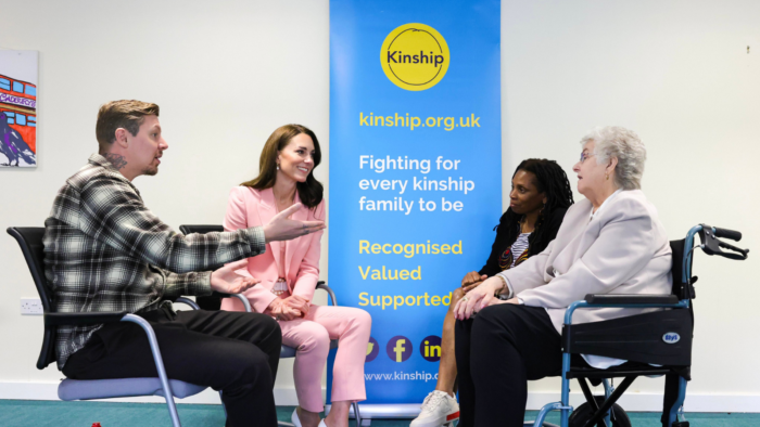 Kate Middleton and Professor Green talking to two kinship carers. Between them is a roller banner with the Kinship logo and text that reads 