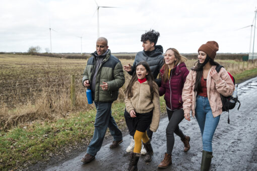 A family smiling and walking together on a muddy road in the countryside.