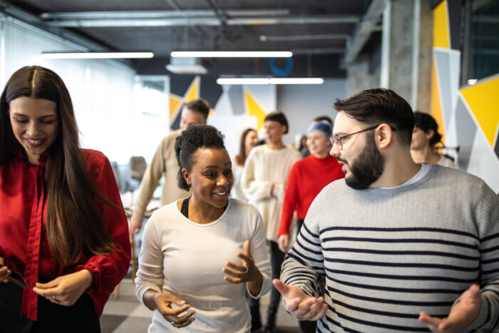 A mixed group of adults walking and chatting inside an office space.