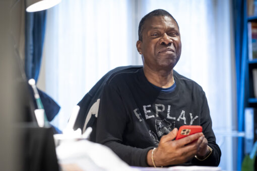 A man sits in his living room holding a mobile phone.