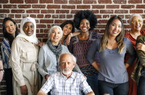 A mixed group of people standing in front of a brick wall.