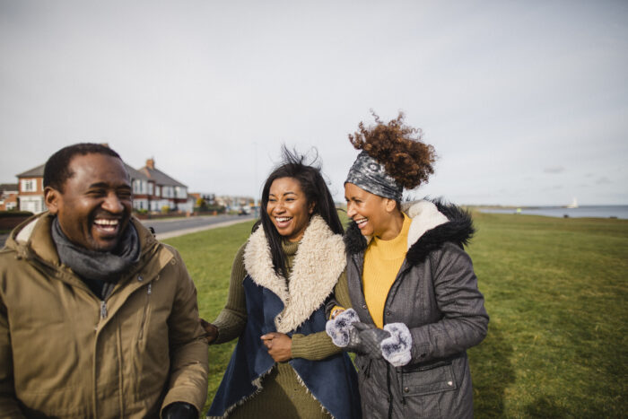 Mother, father and daughter smiling and taking a walk together outdoors by the coast.