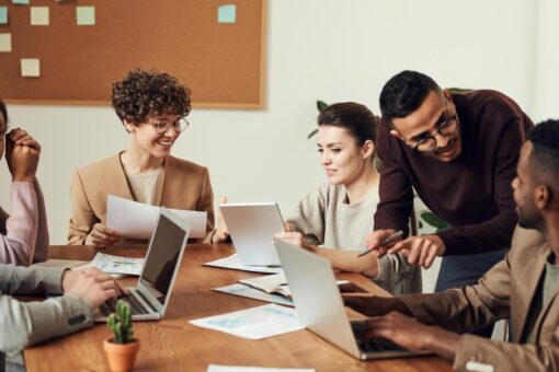 A group of young professionals sitting around a wooden table during a team meeting.