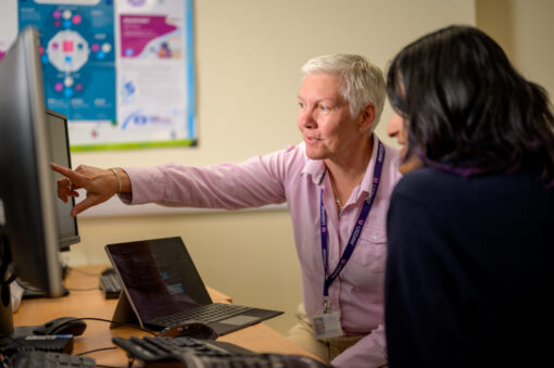 Two colleagues looking at a computer screen. One of them is pointing at something.