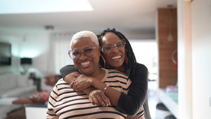 Two women cuddling and smiling in a living room.