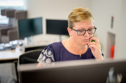 A woman sitting at a computer screen looking deep in concentration.