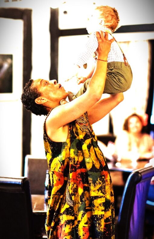 Kinship carer Bobbie-Jo holding the child she cares for in the air.