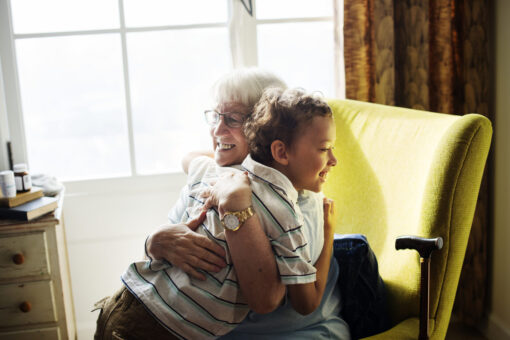 A grandmother sitting in an armchair, hugging her grandson.