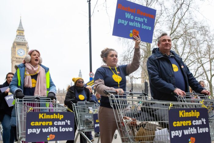 A group of kinship carers marching with empty trollies holding placards saying 