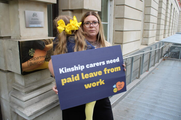 Kinship carer and child standing outside government building calling for paid leave for kinship carers